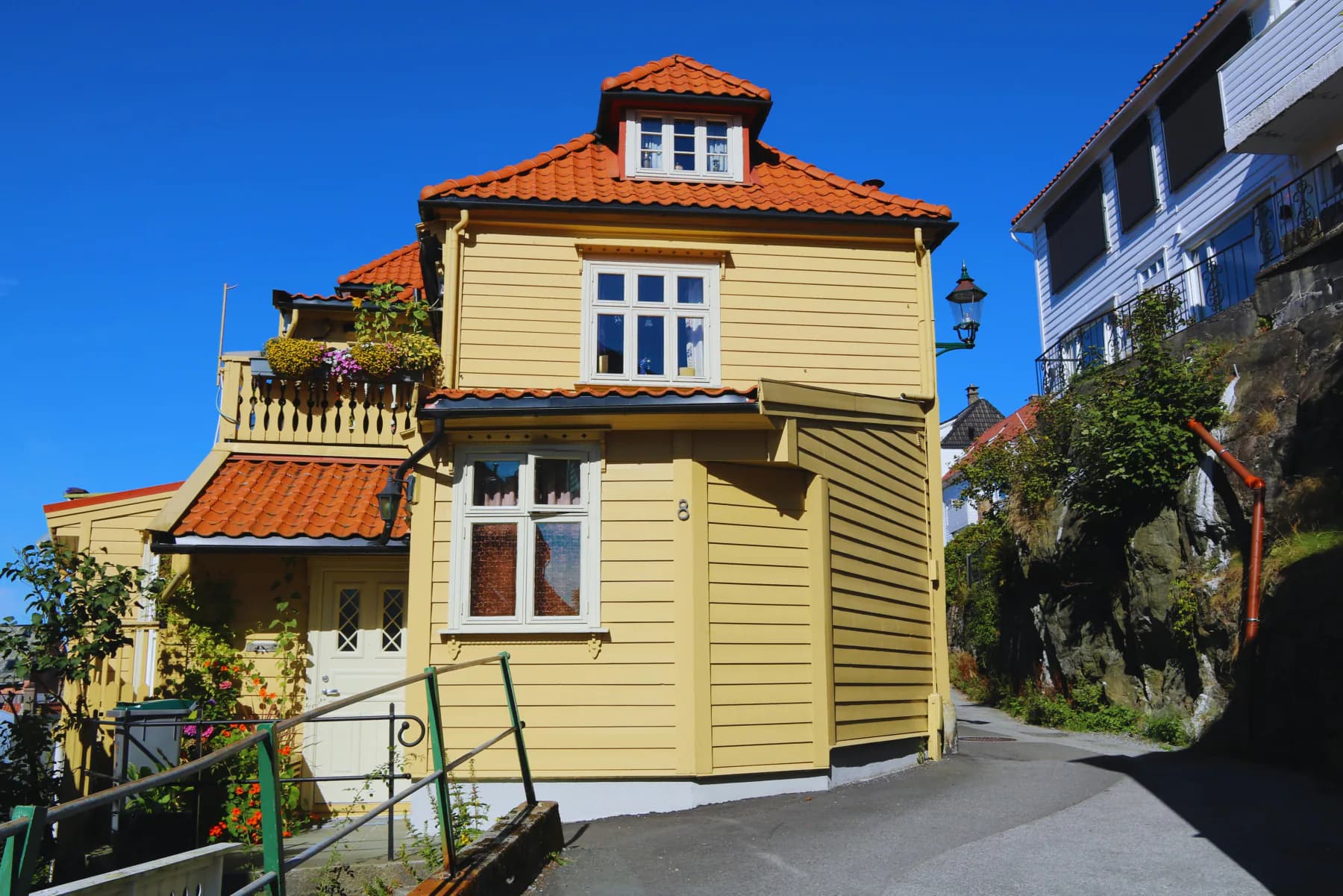 Gult bergenshus med rødt tak i sol — en bolig i overgangen mellom kjøp og salg